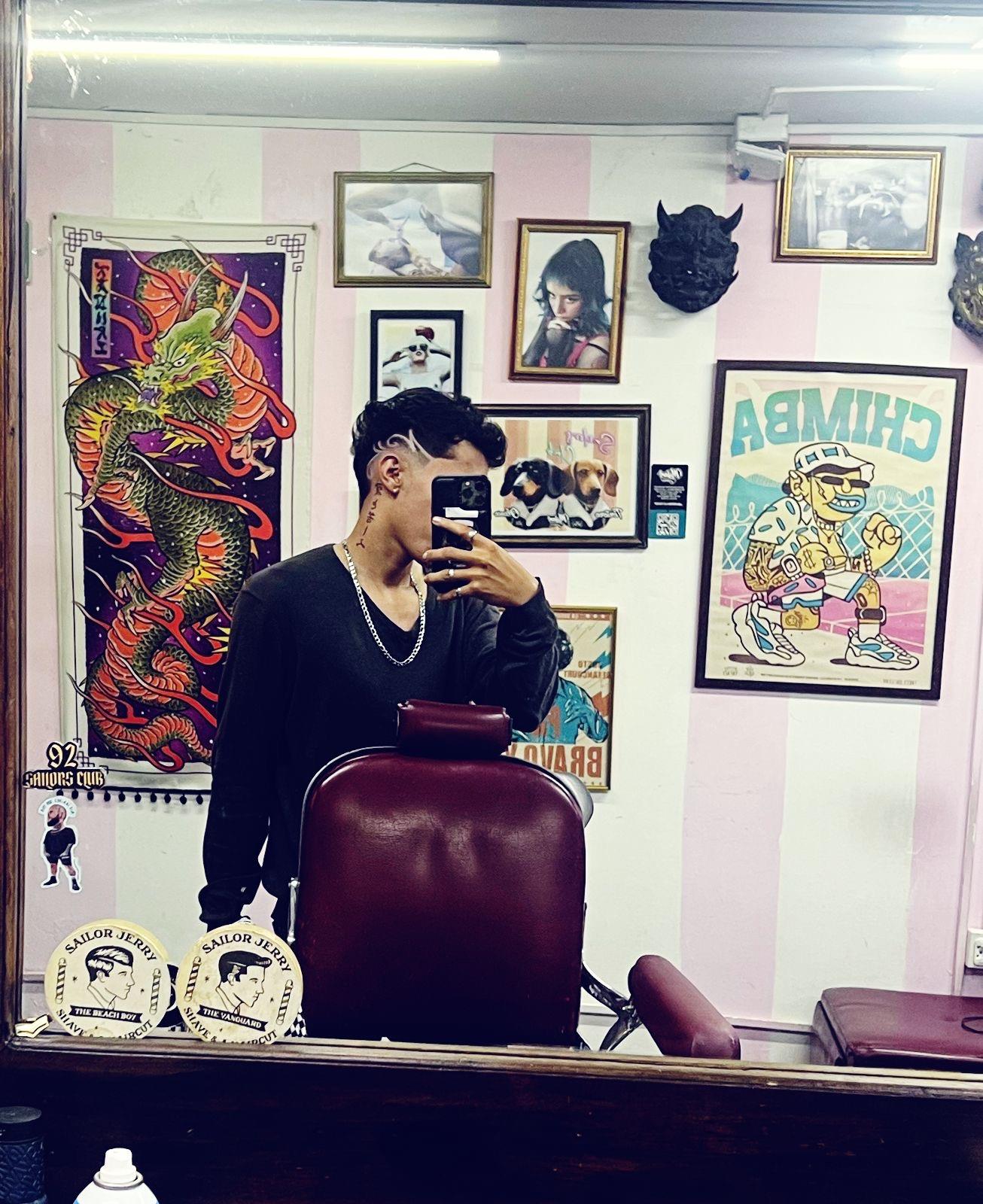 Interior de Sailors Club: paredes a rayas rosa y blanco, cuadros, dragón pintado y silla de barbero
