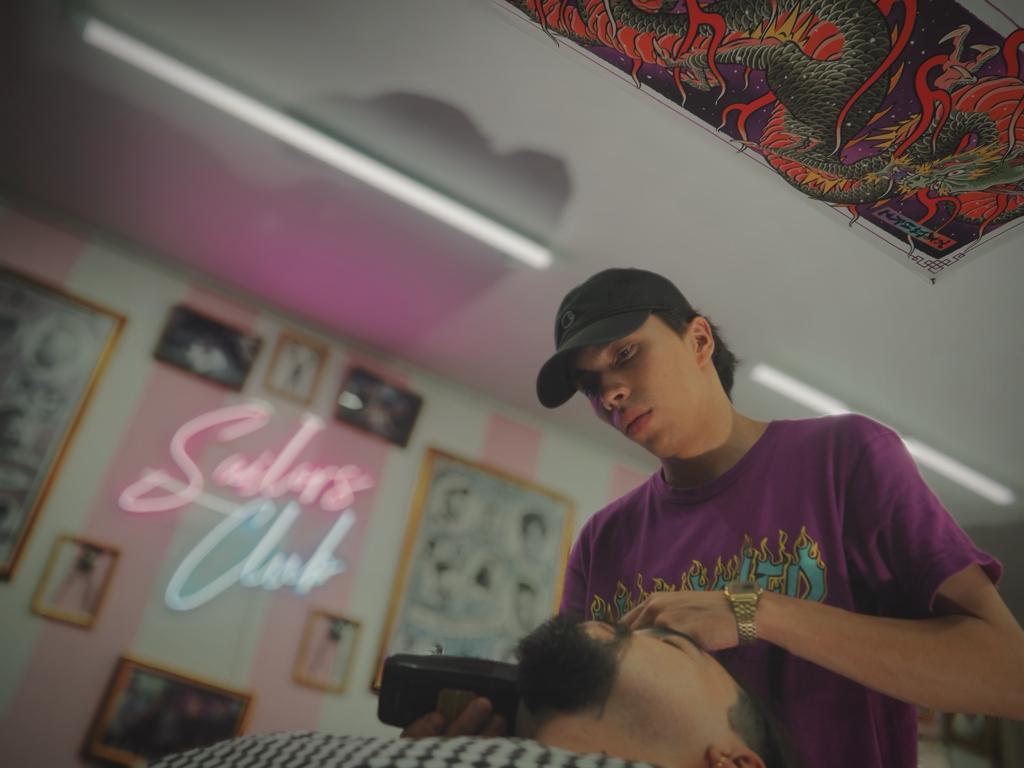 Barbero de Sailors Club trabajando bajo el neón rosado y menta del club